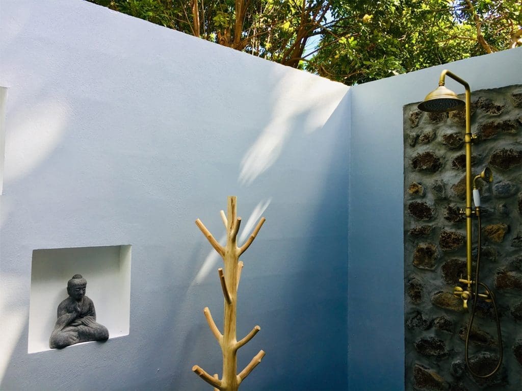 Outdoor shower surrounded by blue walls and stone